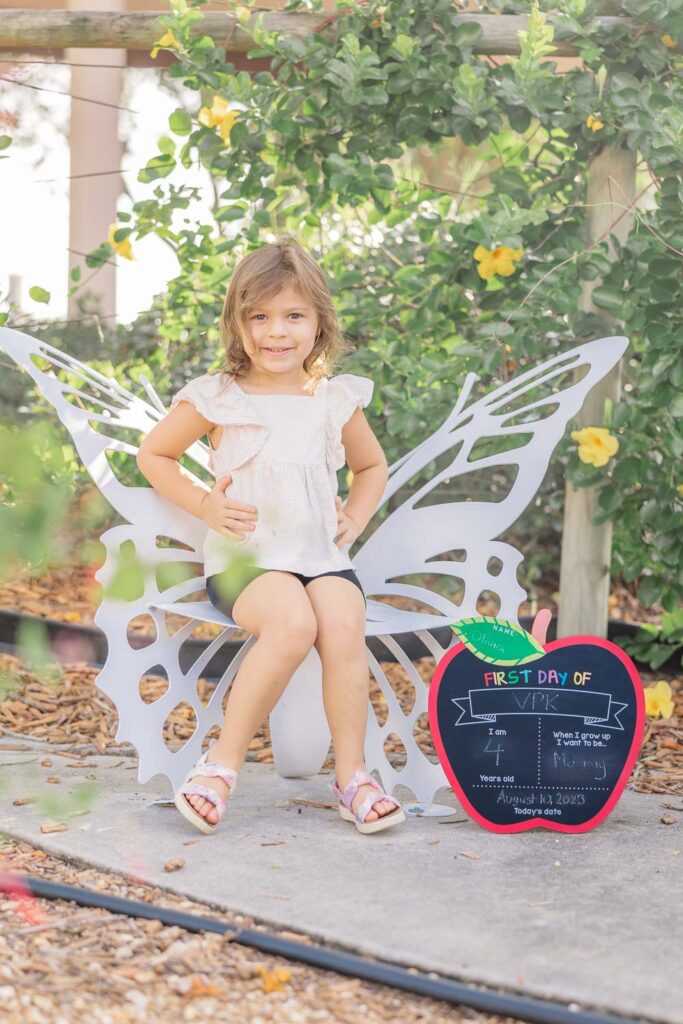 cute little girl poses on butterfly chair in cocoa village.