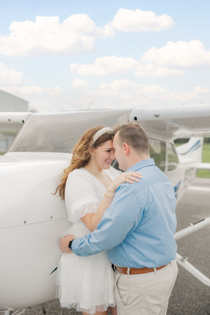 engaged couple in front of airplane