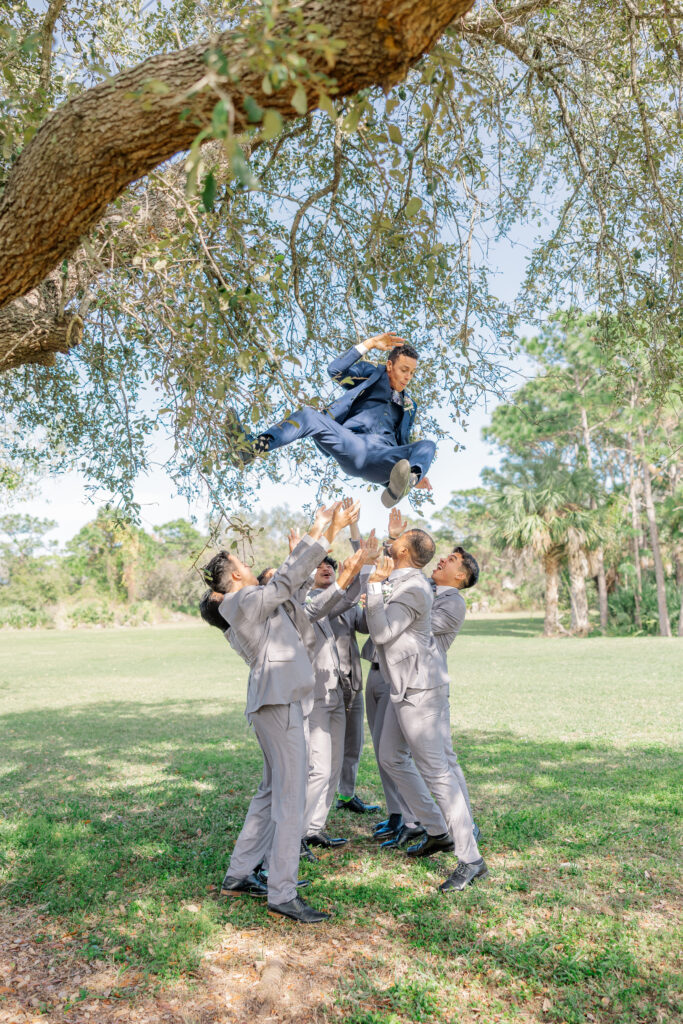 groomsmen tossing groom into the air