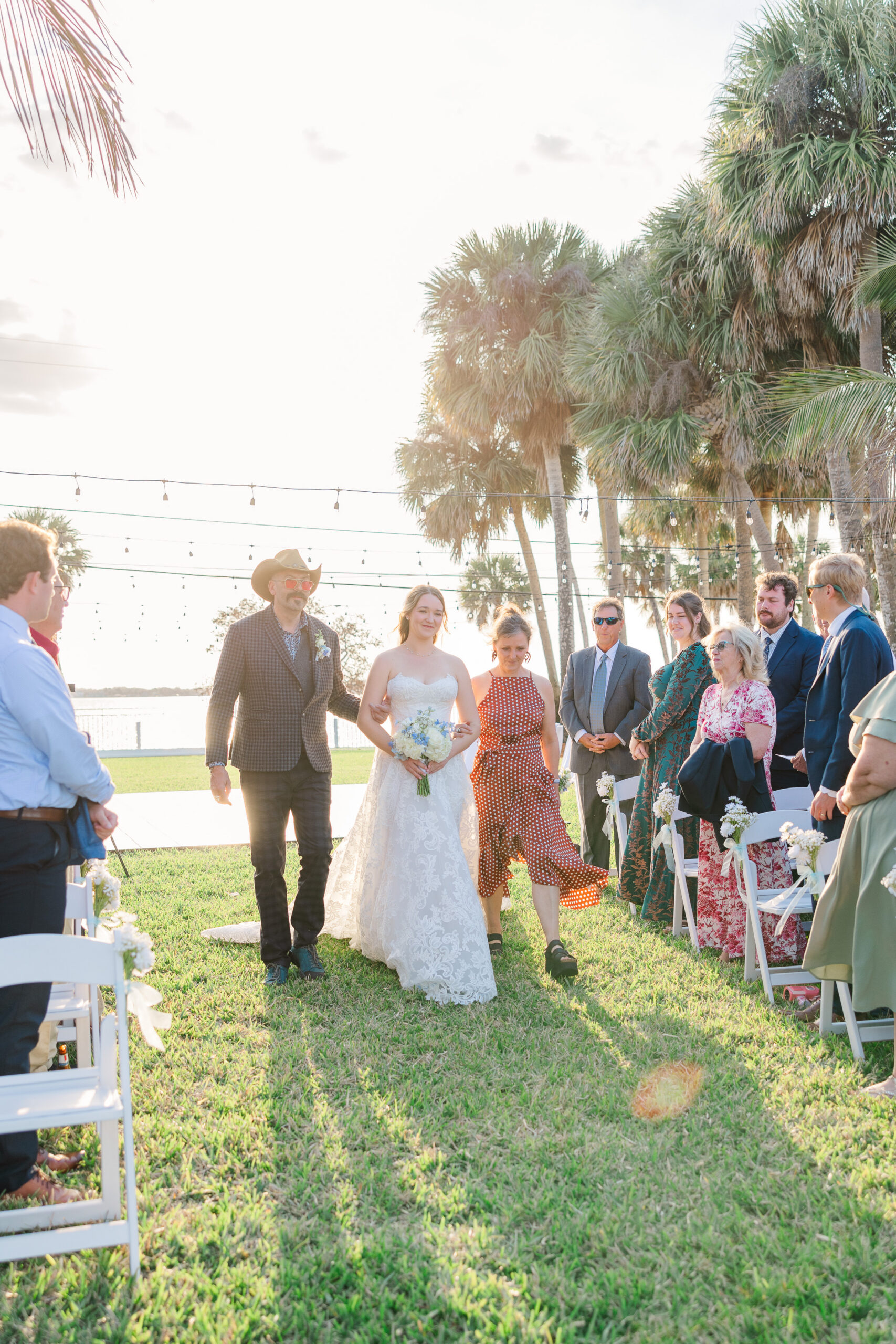 Bride walking down aisle with both parents at Merritt Island backyard wedding