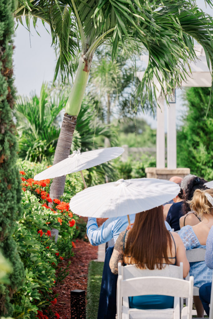 wedding guests using paper parasols